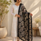 Woman wearing a white outfit with a black floral dupatta in an indoor setting.