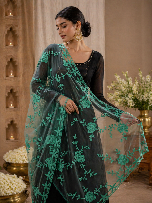 Woman wearing a black outfit with green floral embroidery in a decorative setting.