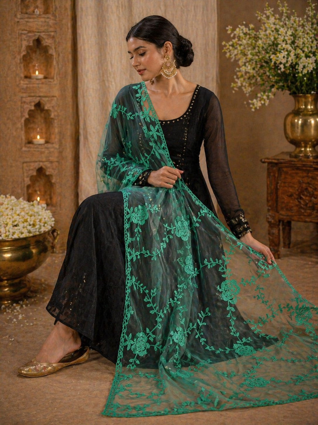 Woman in black outfit with green embroidered dupatta in a decorative setting