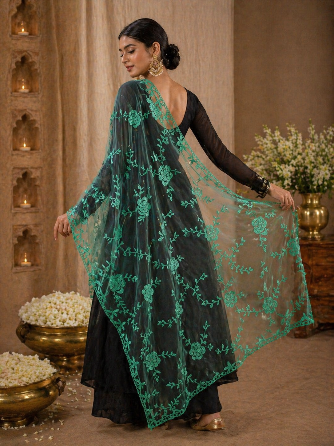 Woman wearing a black outfit with a green embroidered dupatta in an indoor setting.