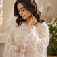 Woman wearing a light-colored embroidered outfit with a neutral background