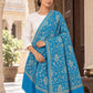 Ferozi blue patterned shawl in an elegant one-shoulder drape on a female model in an Indian heritage haveli