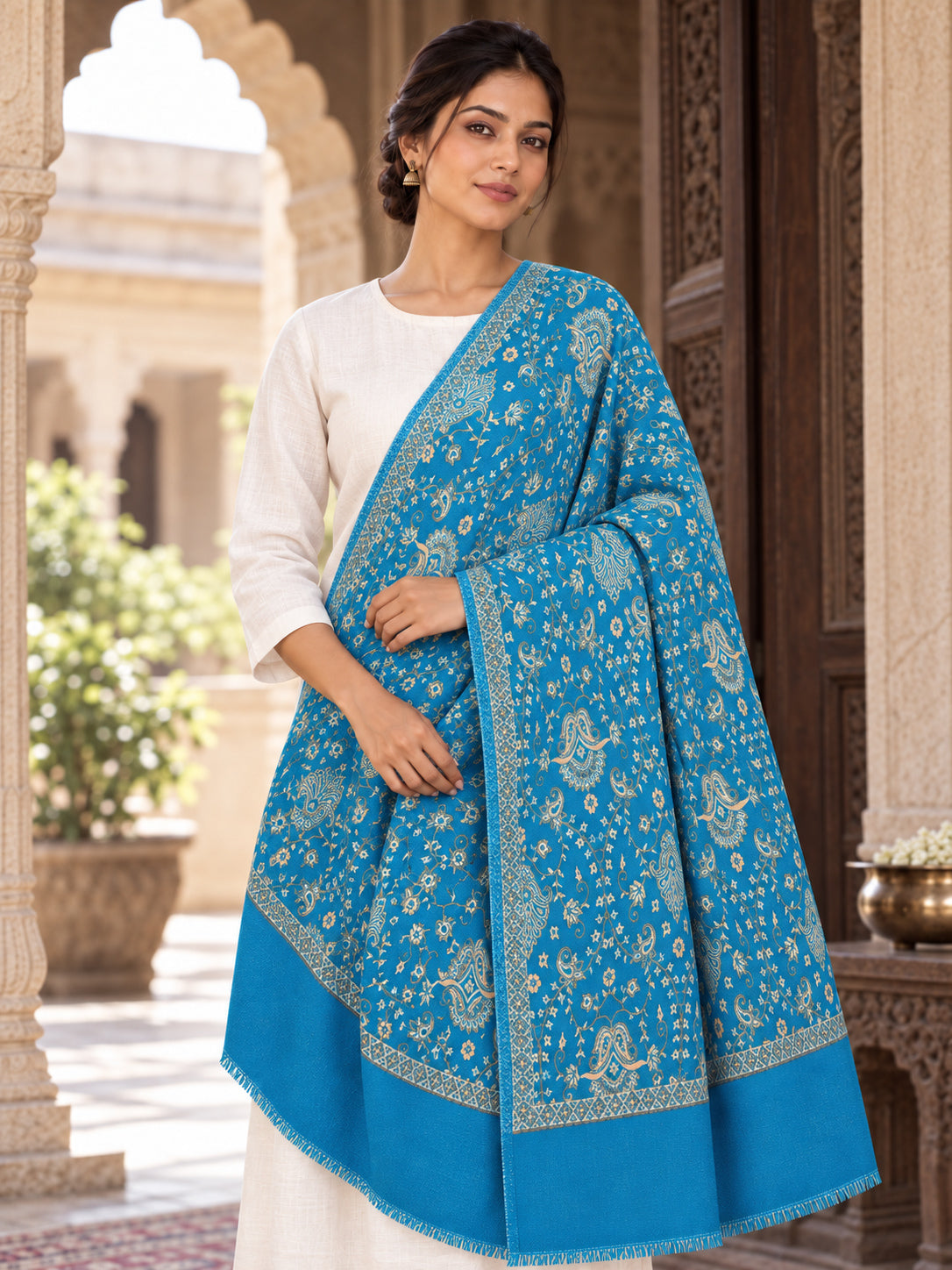 Ferozi blue patterned shawl in an elegant one-shoulder drape on a female model in an Indian heritage haveli