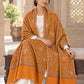 Mustard patterned shawl displayed across the lap of a seated female model in an ethnic heritage setting