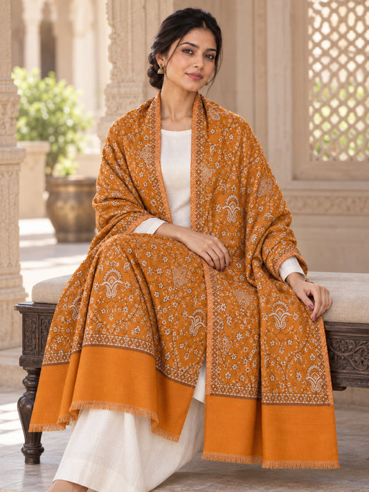 Mustard patterned shawl displayed across the lap of a seated female model in an ethnic heritage setting