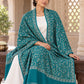 Green patterned shawl in an elegant seated wrap on a female model in an Indian heritage haveli