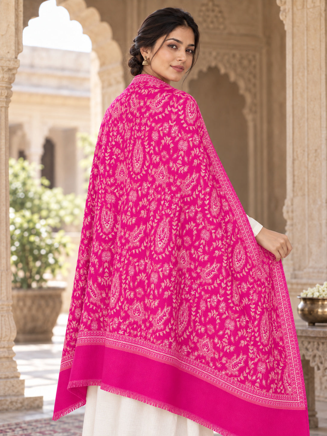 Rani pink patterned shawl in an elegant rear drape on a female model in an Indian heritage haveli