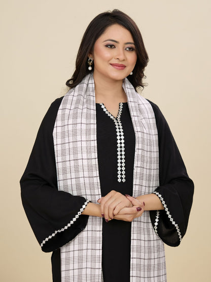 Woman wearing a black and white checkered scarf with a plain background