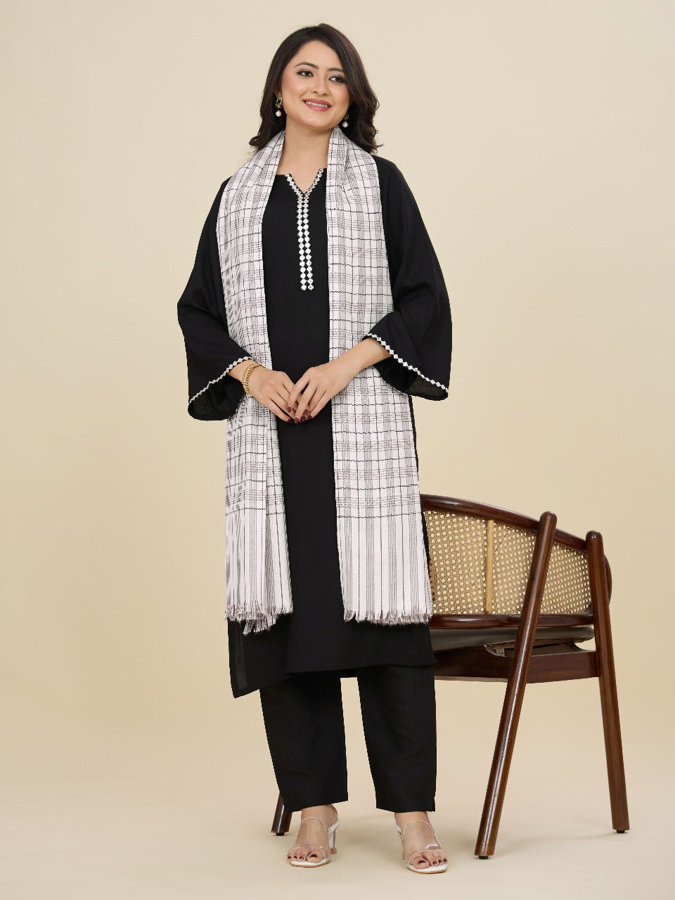 Woman wearing a black and white outfit with a checkered scarf on a beige background