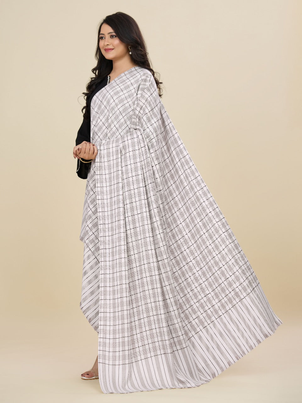 Woman wearing a white and gray checkered saree on a beige background