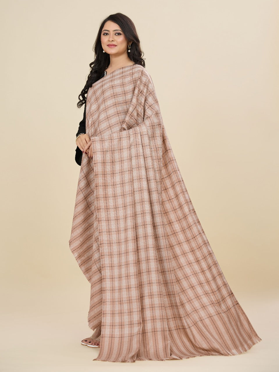 Woman wearing a long, checkered dress against a beige background