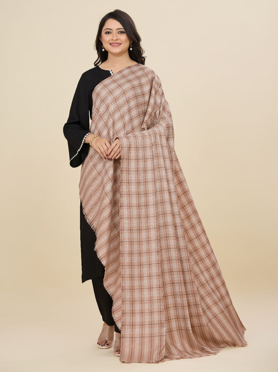 Woman wearing a brown checkered dupatta over a black outfit on a beige background