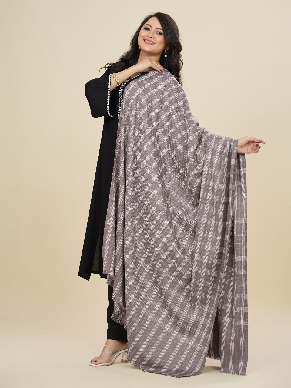 Woman holding a checkered scarf against a beige background