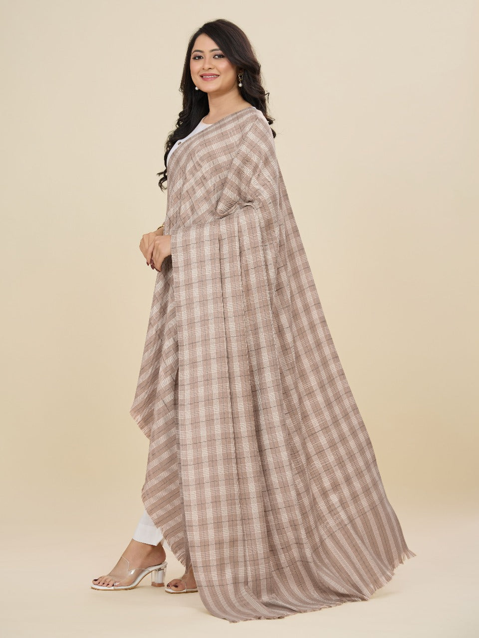 Woman wearing a long, checkered dress with a plain background