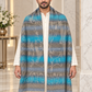 A man wearing a white kurta and a large patterned shawl draped over his shoulders. The shawl features horizontal stripes in shades of blue, gray, and beige with a woven tree motif and cream fringe at the bottom, set against a marble interior background.