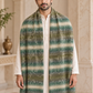 A man wearing a large striped knit shawl with green, beige, and brown tones over a white kurta, standing in an ornate indoor setting with arches.