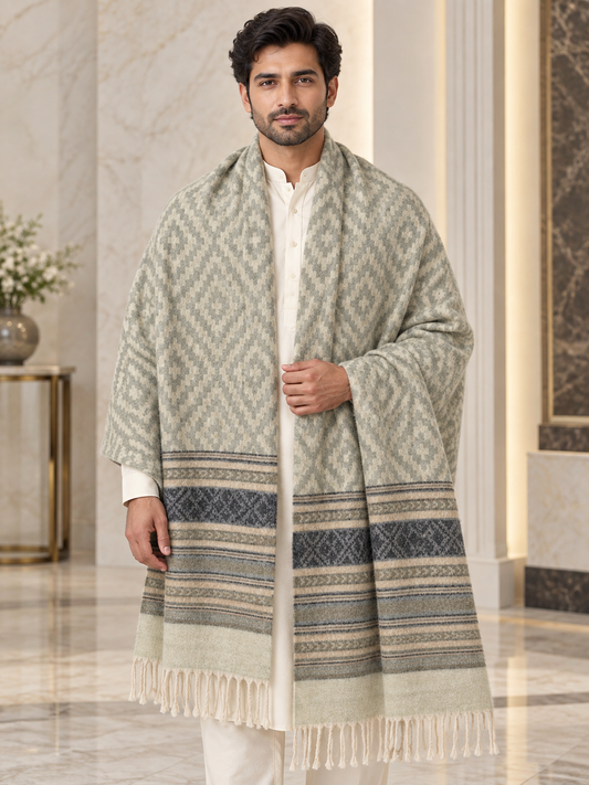 A man wearing a long, patterned shawl over a white kurta in an elegant indoor setting with marble walls and floors.