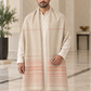 A man wearing a long cream-colored shawl with peach-pink horizontal stripes and fringe, draped over a white kurta in a grand indoor setting with marble floors.