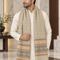 A man wearing a cream kurta and a beige patterned scarf with brown and peach geometric bands, standing in a marble-floored indoor setting.