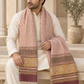 A man wearing a cream kurta sits on a stone bench draped with a patterned scarf. The scarf features a dusty pink upper section with intricate white motifs, a mustard yellow middle band with geometric patterns, and a deep burgundy lower section with white fringe.