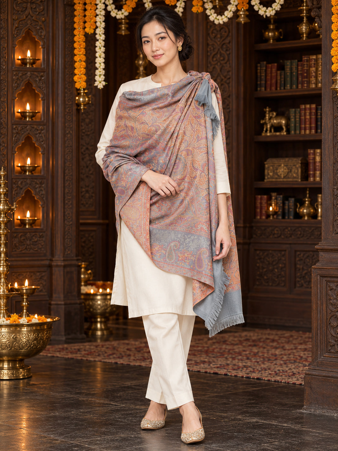 Grey paisley woven shawl styled on a model in a luxurious festive palace setting — single-shoulder styling
