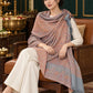 Grey paisley woven shawl styled on a model in a luxurious festive palace setting — seated salon