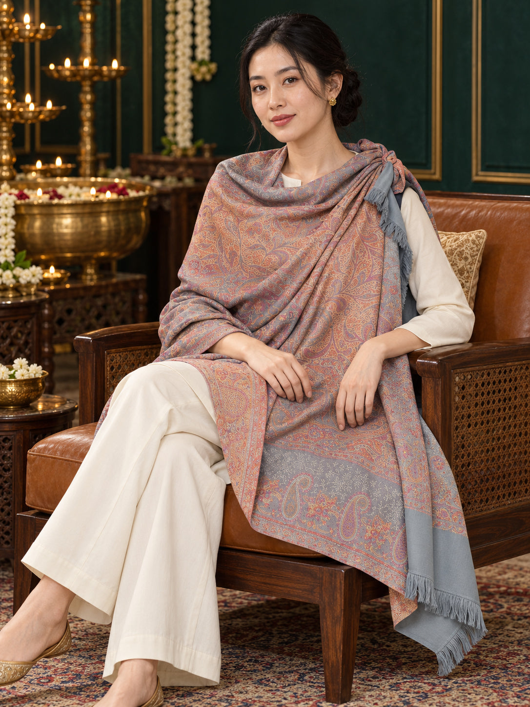 Grey paisley woven shawl styled on a model in a luxurious festive palace setting — seated salon