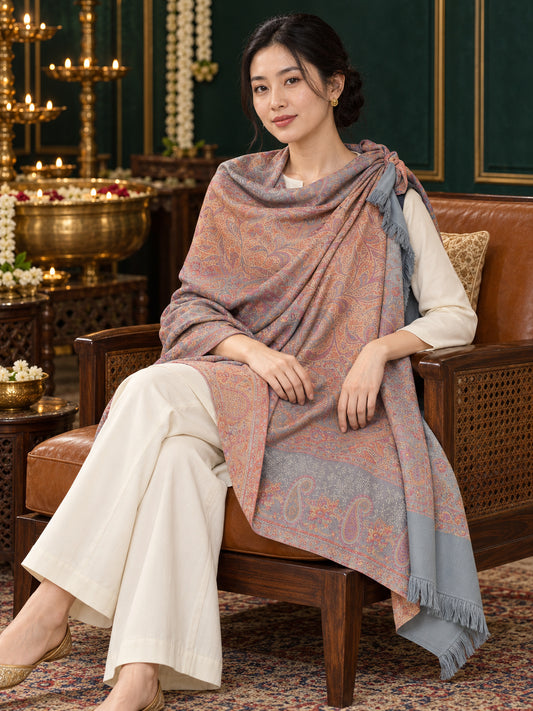 Grey paisley woven shawl styled on a model in a luxurious festive palace setting — seated salon