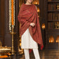 Maroon paisley woven shawl styled on a model in a luxurious festive palace setting — single-shoulder styling