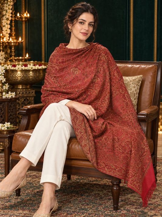 Maroon paisley woven shawl styled on a model in a luxurious festive palace setting — seated salon