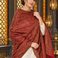 Maroon paisley woven shawl styled on a model in a luxurious festive palace setting — detailed shoulder wrap