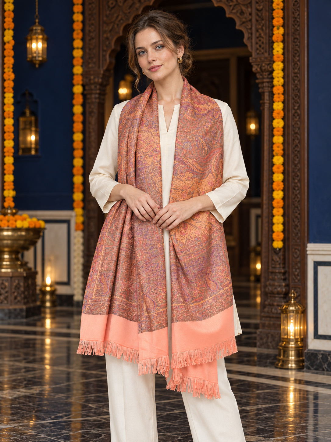 Peach paisley woven shawl styled on a model in a luxurious festive palace setting — long stole
