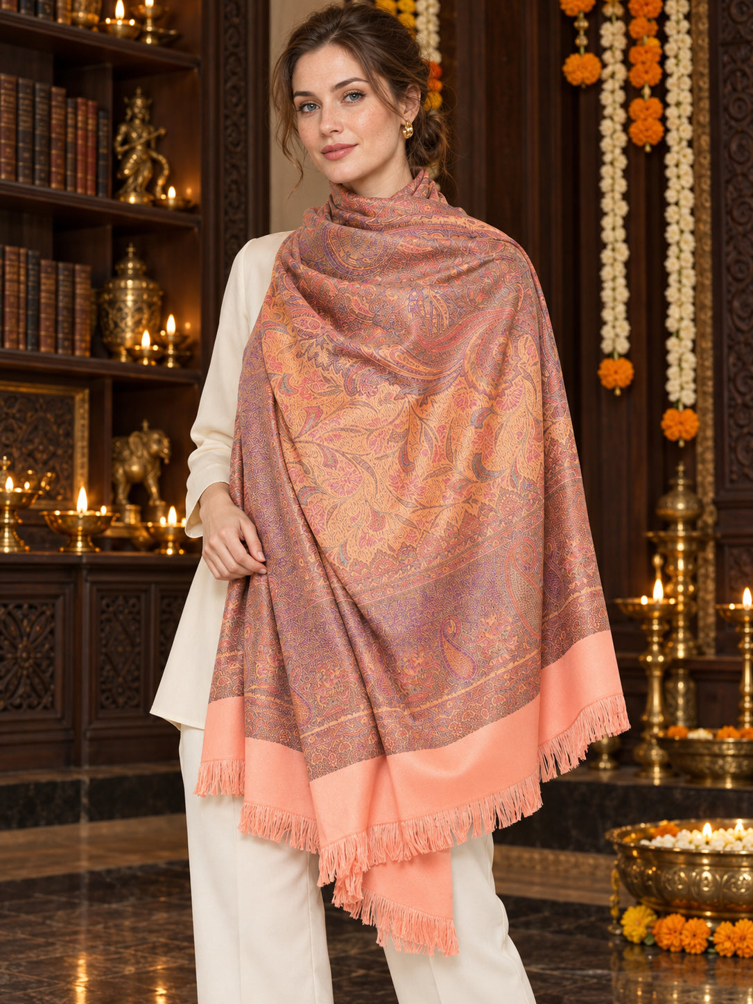 Peach paisley woven shawl styled on a model in a luxurious festive palace setting — single-shoulder styling