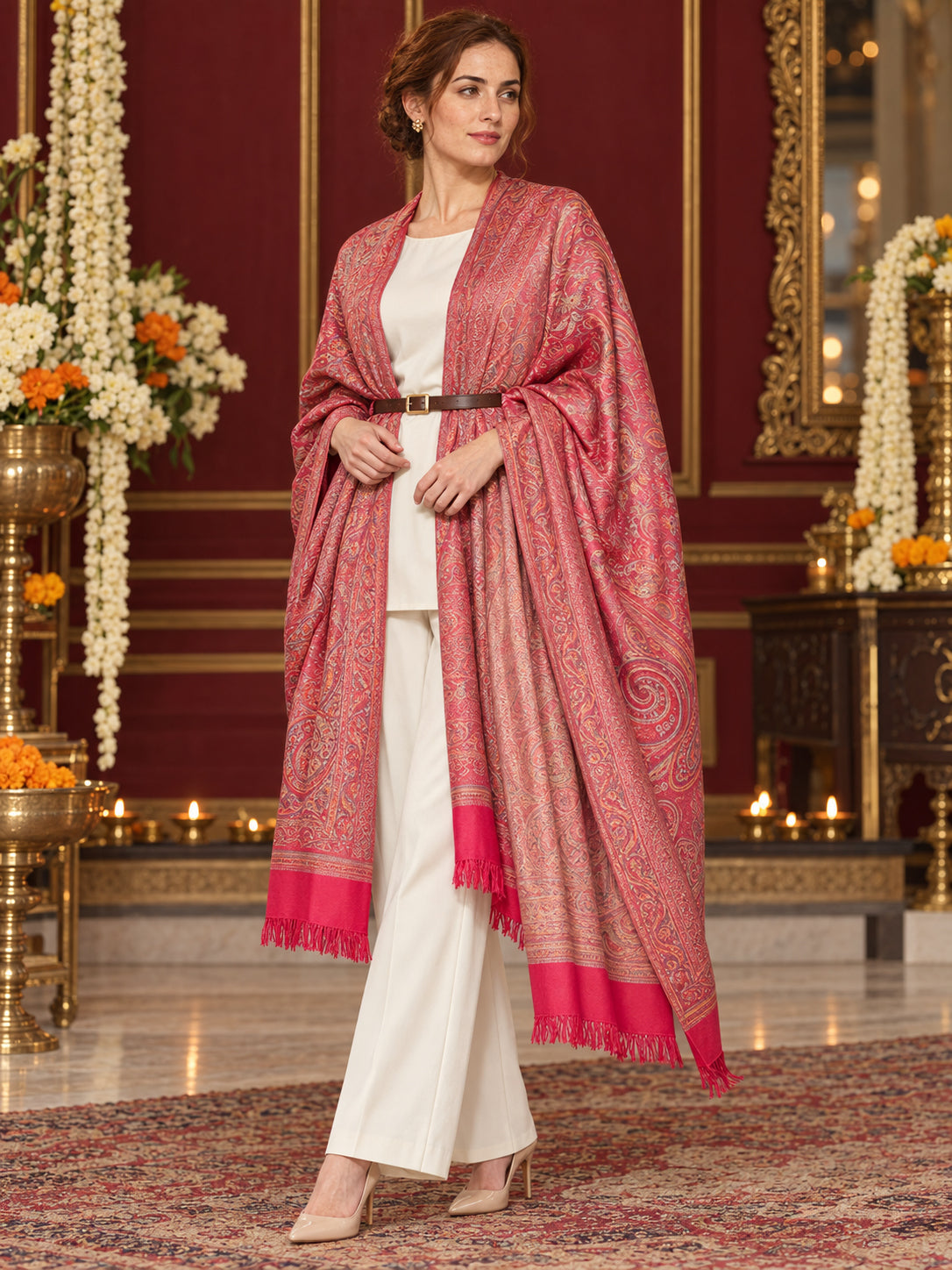 Pink paisley woven shawl styled on a model in a luxurious festive palace setting — belted wrap